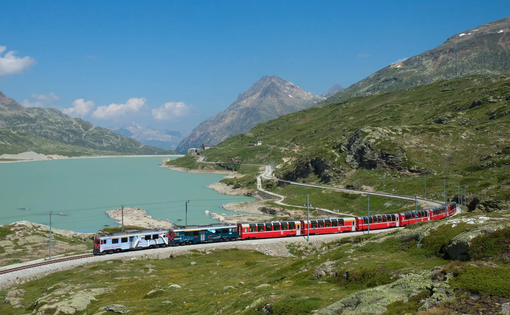 Il trenino rosso del Bernina Express costeggia il Lago Bianco tra le montagne