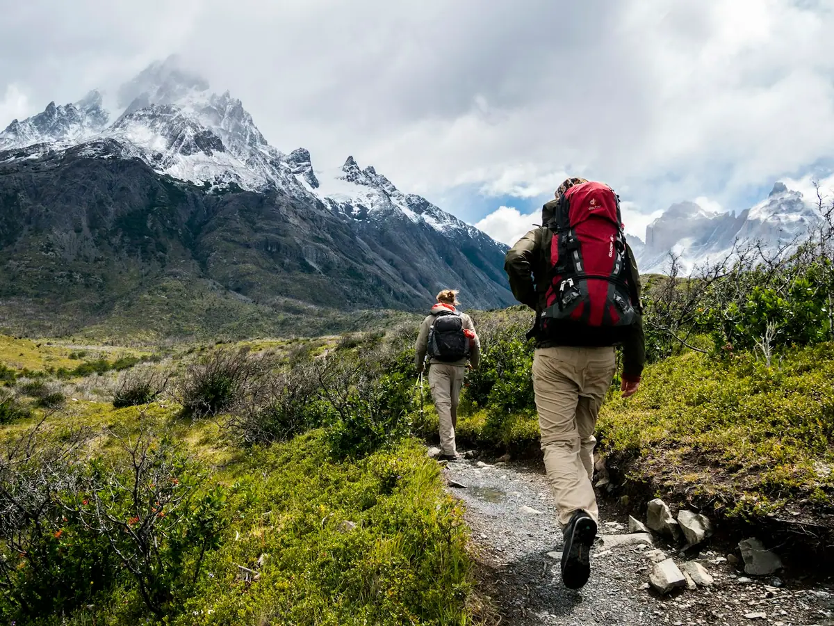 Escursionista su un sentiero di montagna con zaino e bastoncini