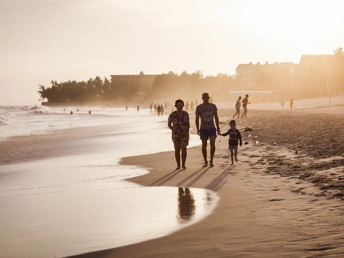 Famiglia con bambini che cammina su una spiaggia al tramonto