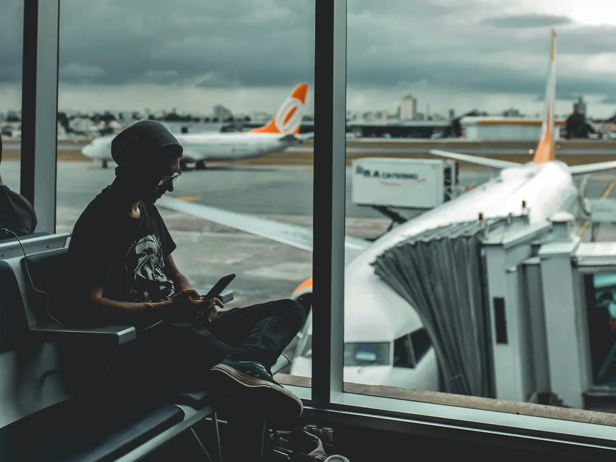 Viaggiatrice con smartphone in aeroporto in contatto con l’assistenza